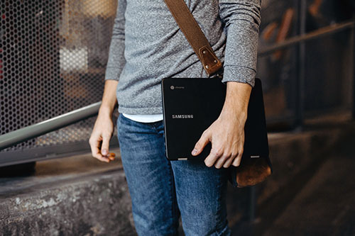 Young man holding a closed laptop