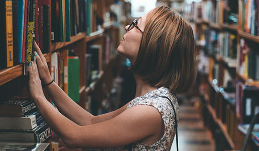 Woman picking a book from a bookshelf