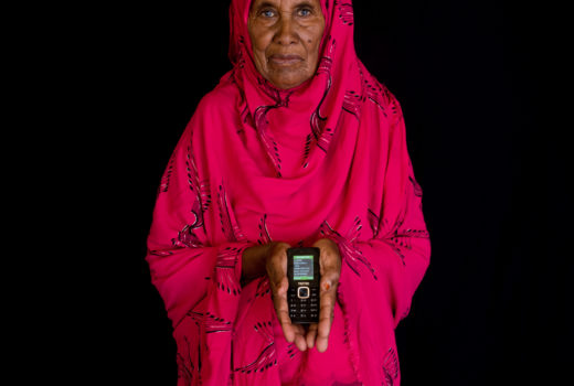 Older woman in red robe holding a mobile phone