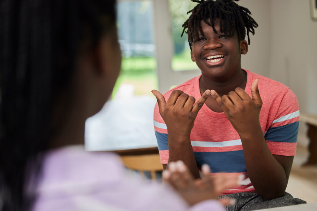 Teenage Boy And Girl Having Conversation Using Sign Language At